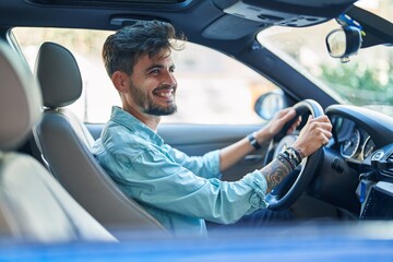 Young hispanic man smiling confident driving car at street