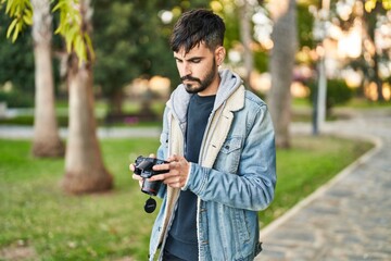 Young hispanic man using professional camera at park