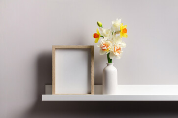 Wooden art frame mockup over grey wall with flowers in vase, blank frame with copy space