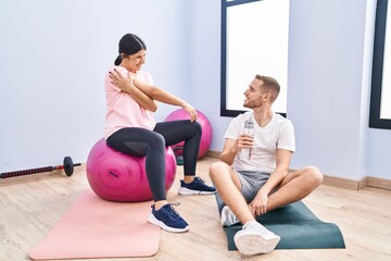 Fototapeta na wymiar Man and woman couple smiling confident stretching and drinking water at sport center