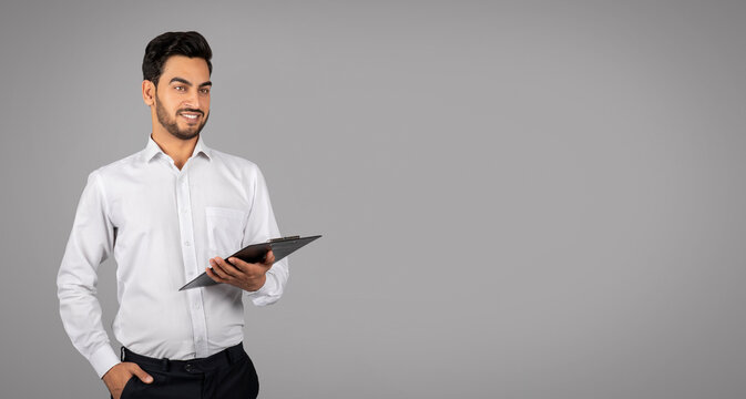 Portrait Of Handsome Young Arab Businessman With Clipboard In Hands
