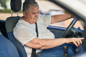 Middle age grey-haired man smiling confident driving car at street