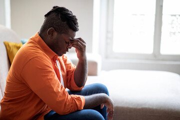 Upset stressed young african man having strong headache, side view