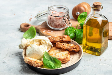 fresh handmade soft Italian cheese from Puglia, white balls of burrata or burratina cheese Basil and Olive Oil and Ciabatta. place for text, top view