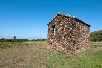 Ancient rural house in ruins on a green field Cap Corse, France