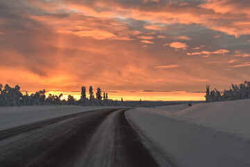 Aerial view of winter forest with frosty trees, rural road and village in Sweden, Lapland