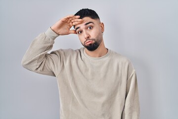 Fototapeta premium Young handsome man standing over isolated background worried and stressed about a problem with hand on forehead, nervous and anxious for crisis
