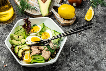 Tuna vegetable vegetarian buddha bowl avocado, egg, cucumber and fresh salad on a dark background....