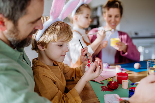 Happy family with little kids decorating easter eggs.