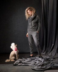 happy girl with a dog in a photo studio on gray. white Poodle and curly woman
