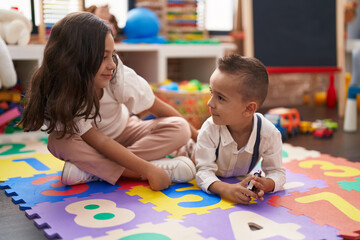 Brother and sister smiling confident sitting on floor at kindergarten