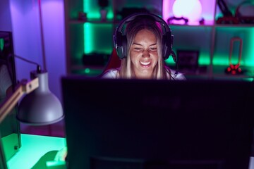 Young beautiful hispanic woman streamer playing video game using computer at gaming room