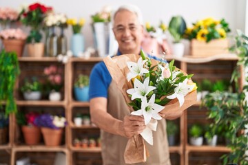 Middle age grey-haired man florist holding bouquet of flowers at florist