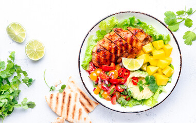 Grilled chicken breast salad with avocado, mango, tomato salsa, cilantro and lettuce in mexican...