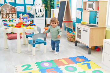 Adorable hispanic toddler standing with relaxed expression at kindergarten