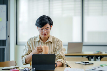 Young asian businessman sitting working with laptop computer in office