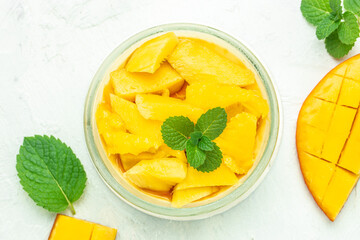greek yogurt and mango in glass jars on a light background. Restaurant menu, dieting, cookbook recipe top view