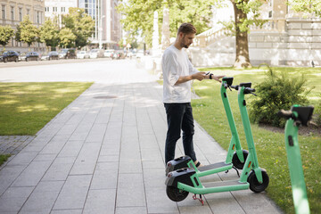 Sustainable Mobility Young Man Unlocks the Future of City Transportation with an Electric Scooter and Mobile Phone. The Key to Achieving Green and Climate Neutral Cities