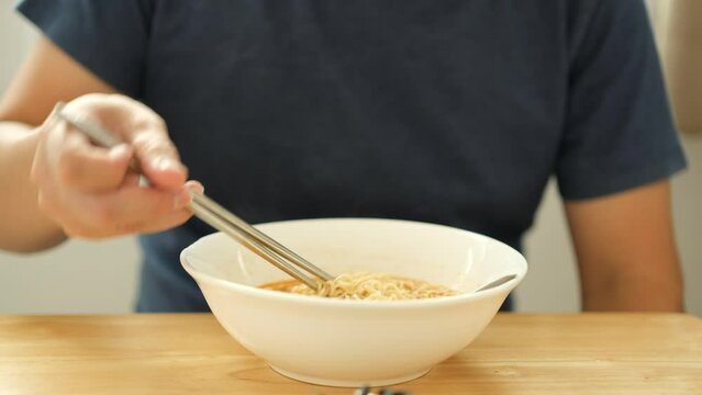 Asian man eating  instant noodles  in a white bowl with sound	