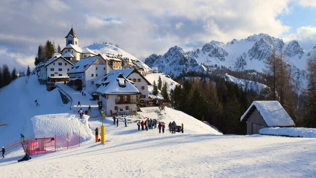 People walking and skiing on The Monte Santo di Lussari, Italy. Winter activities and sports. Adventurous lifestyle. Ski resort in the Italian mountains. Vacation and holidays with family.  