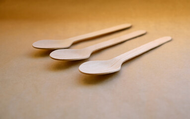 Close-up texture of ecological disposable wooden spoons of natural light color, on harmonious craft paper. Selective focus
