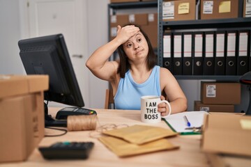 Hispanic girl with down syndrome working at small business ecommerce stressed and frustrated with hand on head, surprised and angry face