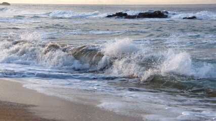 Waves breaking around a rock off a beach in Zipolite, Mexico