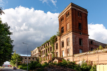The building of an abandoned factory, red brick and broken glass in the windows.