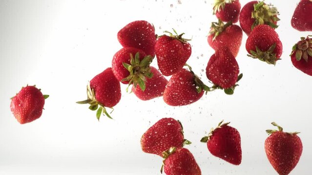 Red strawberry berry falling into transparent water on white background. Sweet fresh berries splashing in aquarium underwater. Healthy organic food air bubbles. Slow motion close-up selective focus