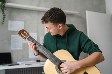 One young man Caucasian teenager sit at home in room playing guitar