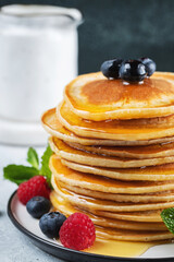 Delicious pancakes, with fresh blueberries, raspberry and maple syrup or honey on a dark background