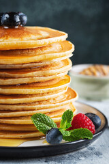 Delicious pancakes, with fresh blueberries, raspberry and maple syrup or honey on a dark background