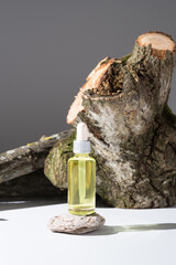 Botella de aceite esencial con cuentagotas sobre un tronco de árbol con musgo. Producto cosmético natural de aromaterapia	