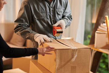 House owner controlling mover sealing cardboard boxes