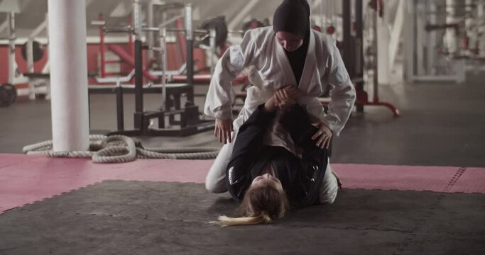 Women practicing grappling holds on floor