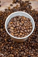 Paper cup of coffee on the background of coffee beans top view. Paper coffee cup with coffee beans