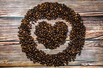 Heart made from coffee beans on a wooden table. The concept of favorite drinks
