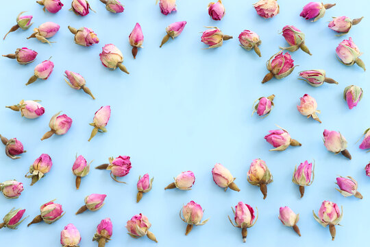 top view of dry roses flowers over blue pastel background with copy space