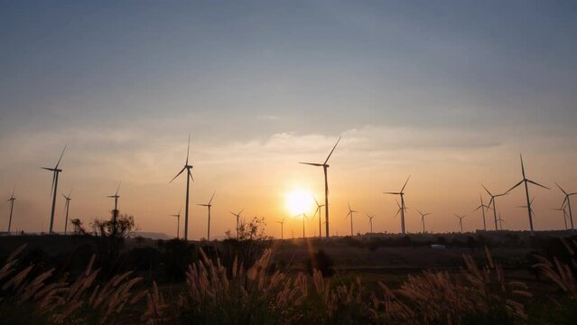 Wind turbine field at sunset Time-lapse photography, sustainable energy It can generate electricity day and night with the wind.