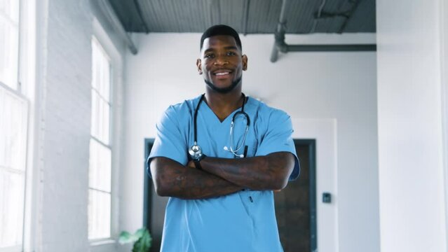 Black Stock Footage portraits of millennial Black man nurse working in a blue medical scrubs in the hospital corridor hallway with natural light