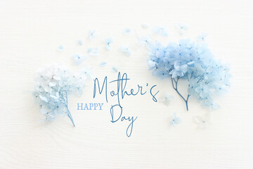 mother's day concept with blue flowers over white wooden background