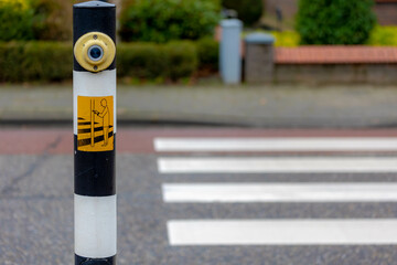 Selective focus of Pedestrian crossing button on the pole, Blurred crosswalk or zebra crossing in...