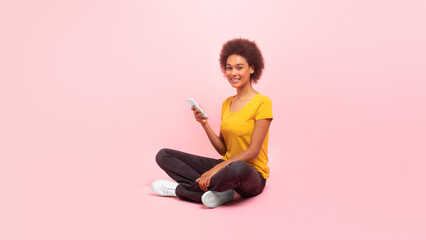 Fototapeta na wymiar Cheerful millennial multiethnic woman in casual typing on smartphone, chatting, watch video, surfing internet