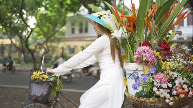 Portrait of Asian peddler with bike and flowers, Vietnamese woman girl traveling in Hanoi urban city town, Vietnam. People lifestyle.
