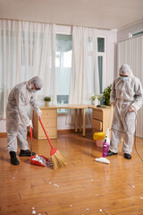 Cleaning service workers wiping floor and desinfecting surfaces in apartment © DragonImages