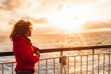 Travel people concept lifestyle. One woman admiring sunset light on the ocean standing on the ferry...