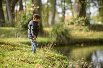 young caucasian boy playing in urban park in autumn