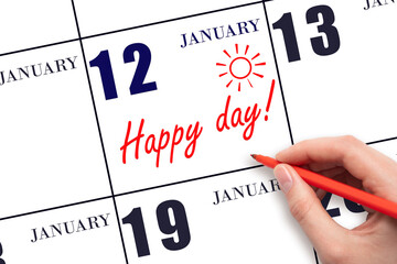 Hand writing the text HAPPY DAY and drawing the sun on the calendar date January 12