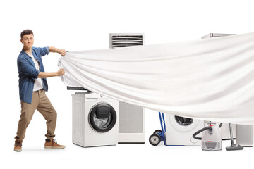 Young man pulling a white piece of cloth in front of home electrical appliances