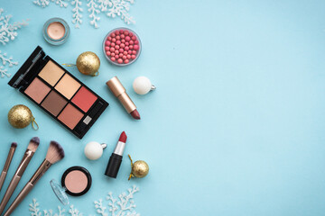 Make up products and winter decorations on blue background. Winter cosmetic. Flat lay image with...